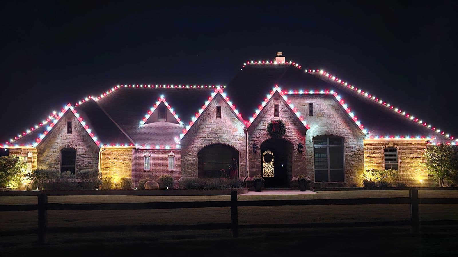 Stone estate home with a full rooftop Christmas light display